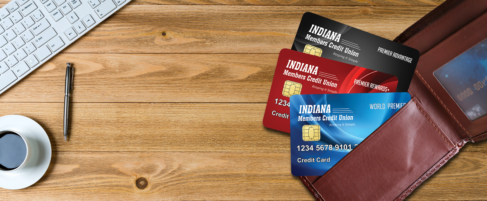 Indiana Members Credit Union credit cards World Premier, Premier Rewards+ and Premier Advantage on top of a wood table.
